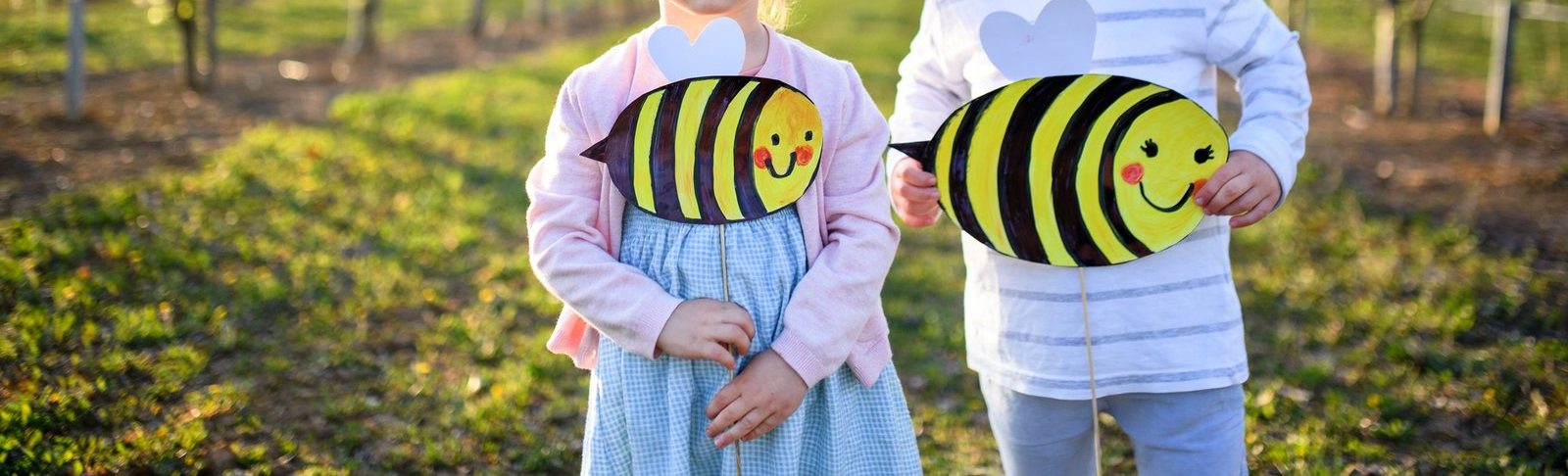 Niños en un campo en flor con abejas de papel pintadas por ellos, en un taller de Neurobee
